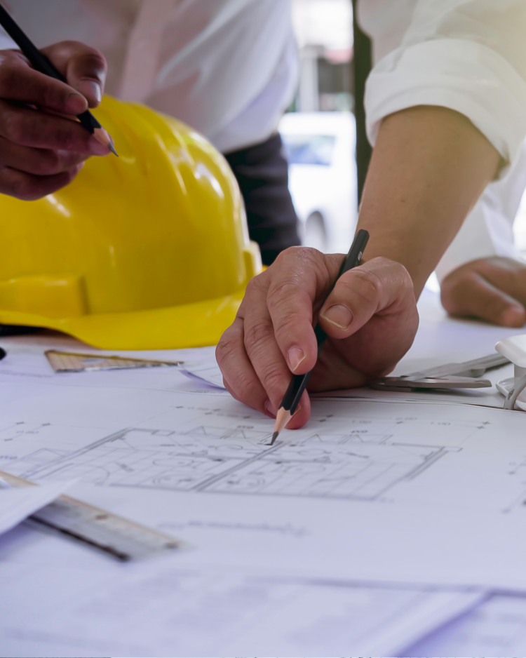 Conseil en énergie – Études et plans techniques pour optimiser l’efficacité énergétique Ingénieurs en conseil en énergie dessinant des plans techniques sur un chantier avec casque de sécurité jaune