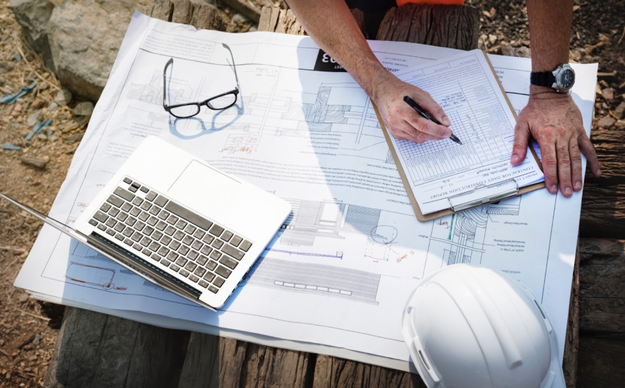 Plan de chantier avec ordinateur et documents techniques pour un projet de GTB gestion technique du bâtiment